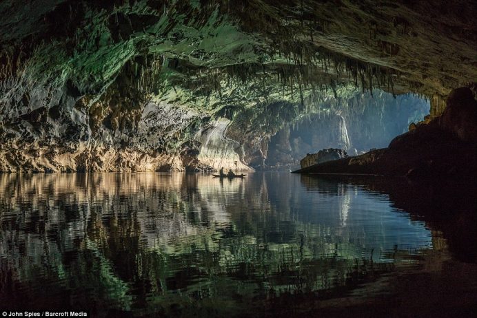 A blue-tinted glow from outside illuminates the entrance chamber of the cave