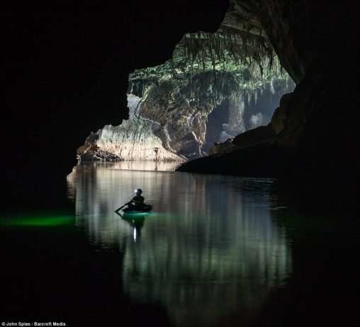 Heading into darkness, a visitor paddles a small canoe near the downstream entrance. In the dry season from November to April, the water is clear and deep with a rich green hue