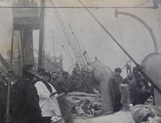 Priest praying over Titanic victims before they are buried at sea