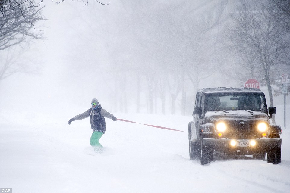 Gary Utley, 27, of Alexandria, snowboards behind a Jeep driven by his friend, as snow falls, in Alexandria, Virginia, on Saturday