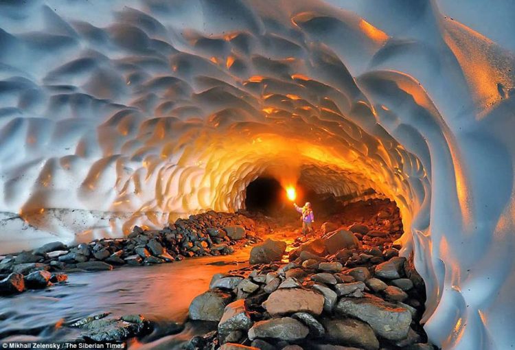 The walls and ceiling of the frozen world are made up of layers of compacted snow, with the river softly gurgling through a long chamber here illuminated by a yellow flare